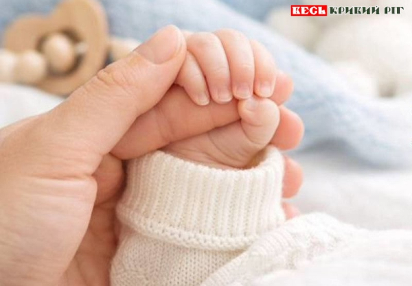 Мати тримає за руку немовля